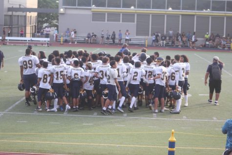 Punahou Intermediate football team in huddle on field